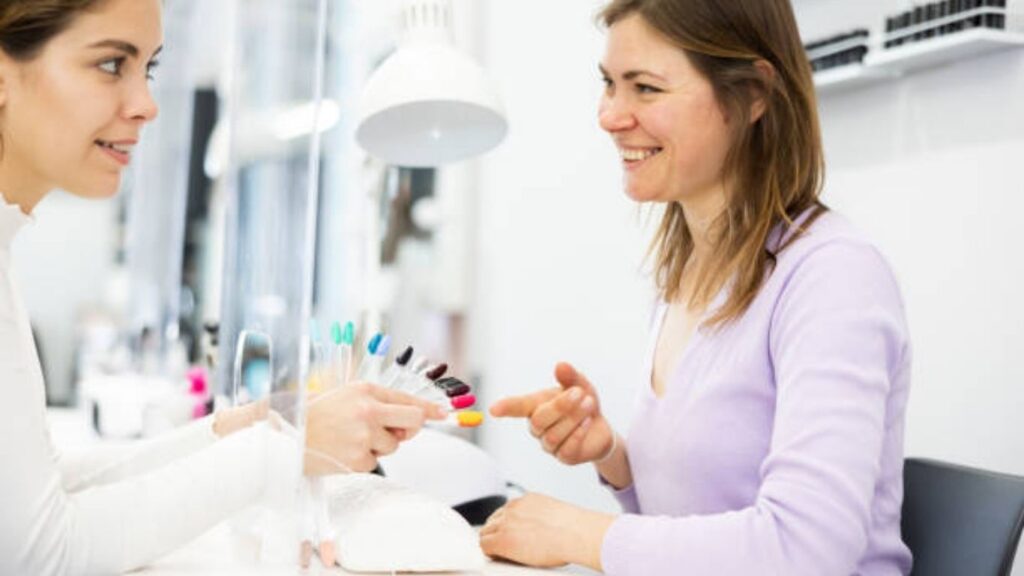 Nail technician observing nail condition during consultation