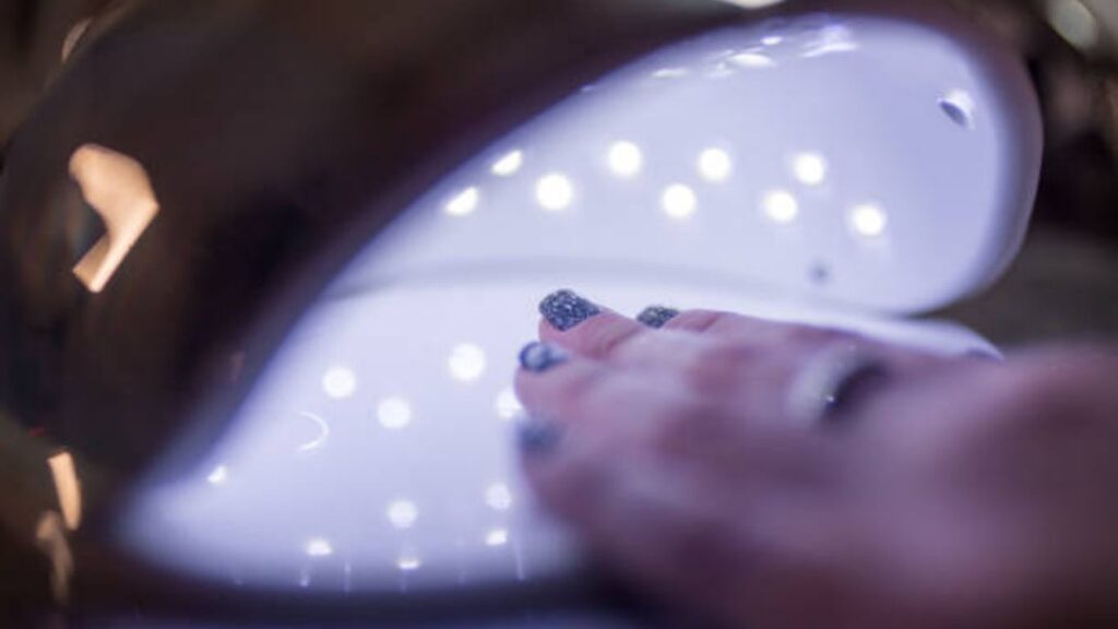 Curing gel polish under LED lamp during professional manicure steps